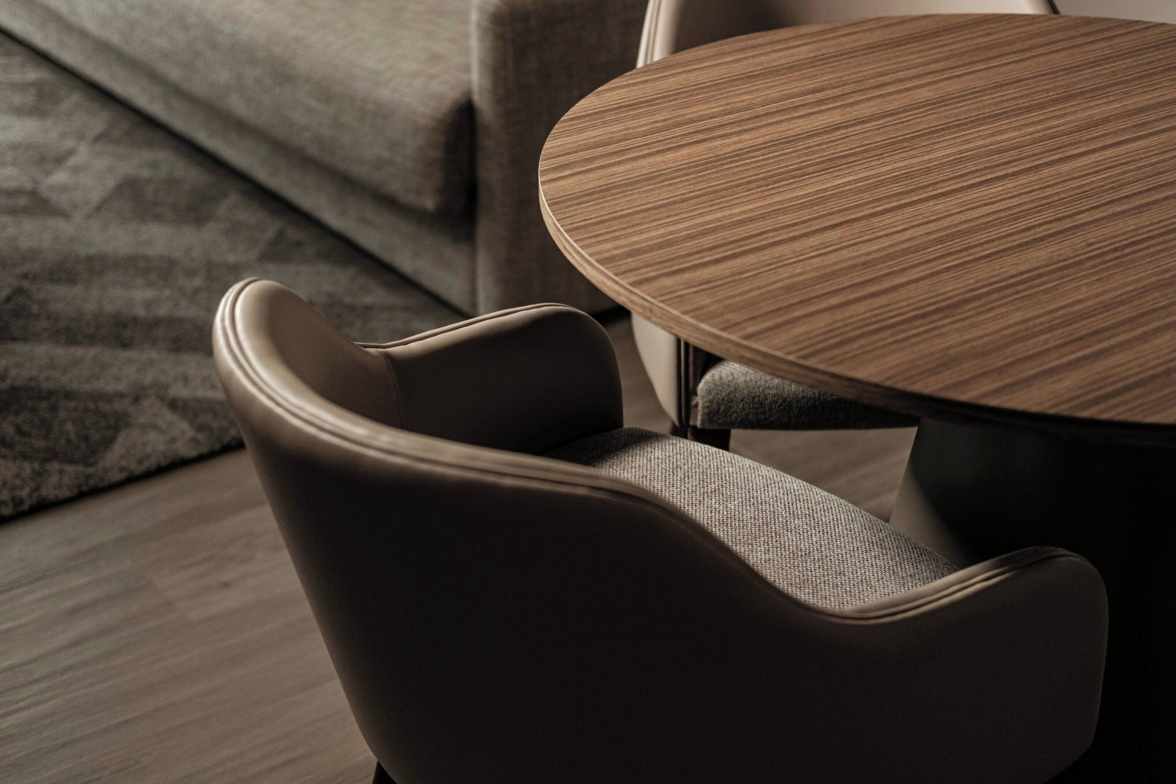 Een moderne woonkamer met een ronde houten salontafel, een donkerbruine bank en een kamerkleed met een patroon.