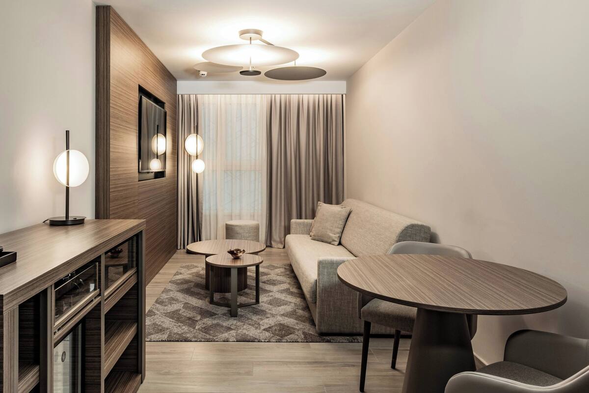 A modern living room with a sofa, two round tables, a coffee table, a TV, and a wooden cabinet.