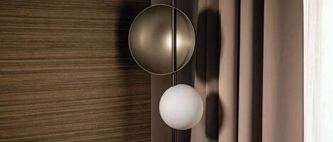 A modern interior with a wooden panel wall, a minimalist light fixture, and a curtain.