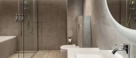 A modern bathroom with a glass-enclosed shower, a white sink, and a toilet.