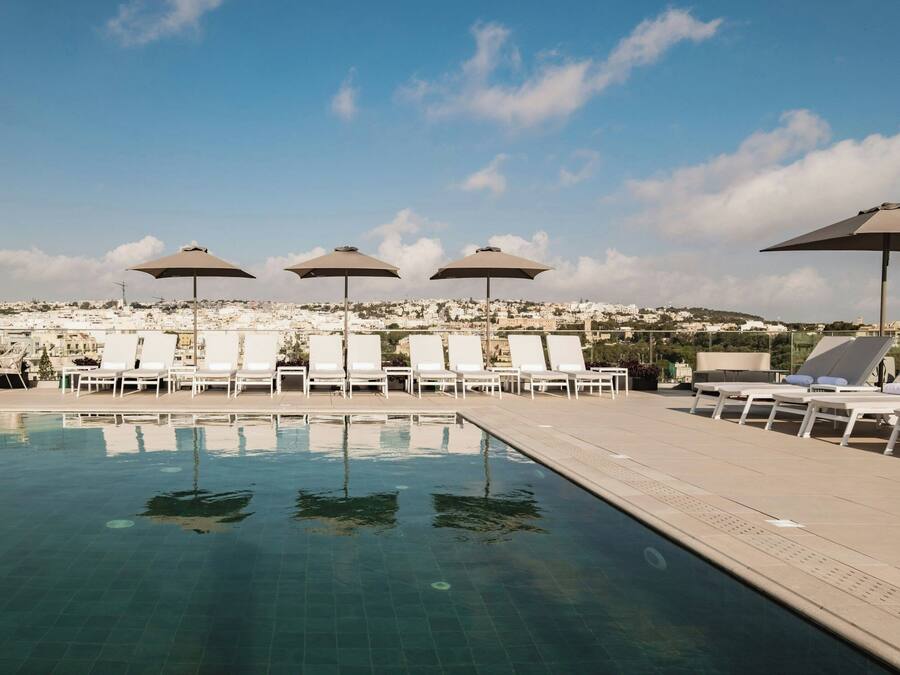 Una piscina techada, una piscina al aire libre, sombrillas