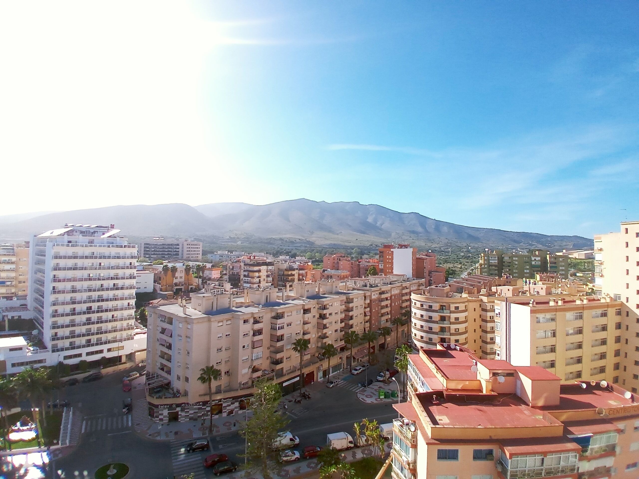 A cityscape with multi-story buildings, a central roundabout, and a mountain in the background.
