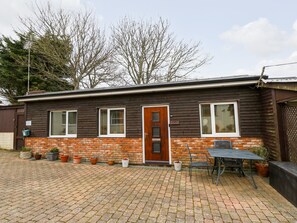 A single-story house with a brick foundation and wooden siding. - The Retreat (Ventnor)