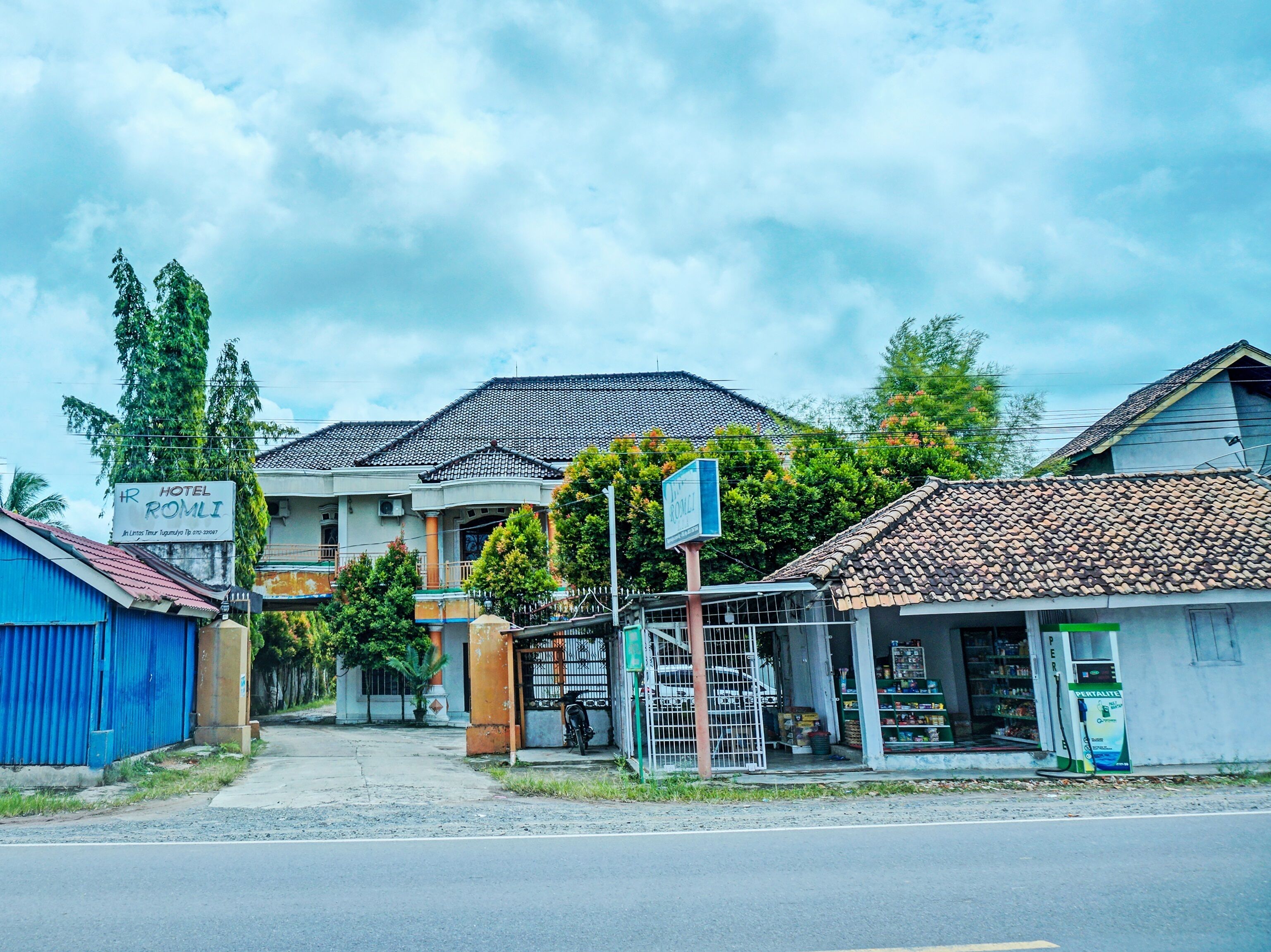 A hotel with a tiled roof, a signboard, and a small shop in front.