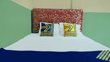 Una cama con sábanas blancas y dos almohadas con diseños azules y amarillos.