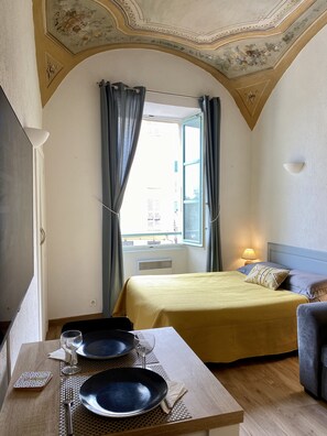 Classic hotel room with a bed, bedside table, and dining area.