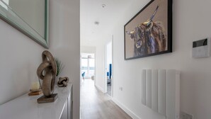 A hallway with a modern design, featuring a sculpture, a framed painting, and a radiator. - Stylish Penthouse- Guests Favourite. Just Amazing! (London)