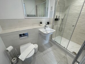 A modern bathroom with a glass shower enclosure, a sink, and a toilet.