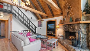 Una sala de estar acogedora con chimenea, un sofá, una mesa de centro y una escalera.