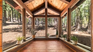 Una cabaña de madera con ventanas amplias que dan a un bosque.