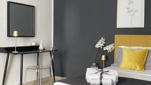 A modern bedroom with a bed, bedside table, and a desk with a lamp. - Ortigia Suite 1939 (Siracusa)