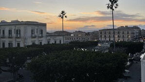 Un paisaje urbano al atardecer con arquitectura clásica, palmeras y cielo despejado.