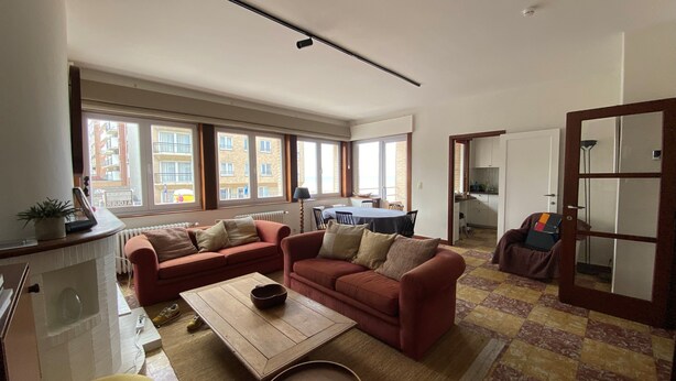 Een woonkamer met een zithoek, een salontafel en uitzicht op het balkon.