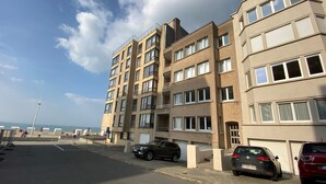 Een meerlaags woongebouw met een parkeerplaats ervoor.