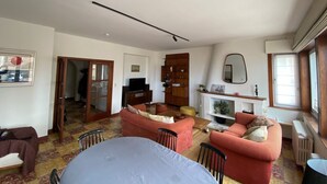 Een woonkamer met een bank, een televisie, een open haard en een spiegel.