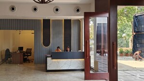 Eine Rezeption mit zwei Mitarbeitern, ein modernes Interieur mit vertikalen Paneelen und Blick ins Freie.