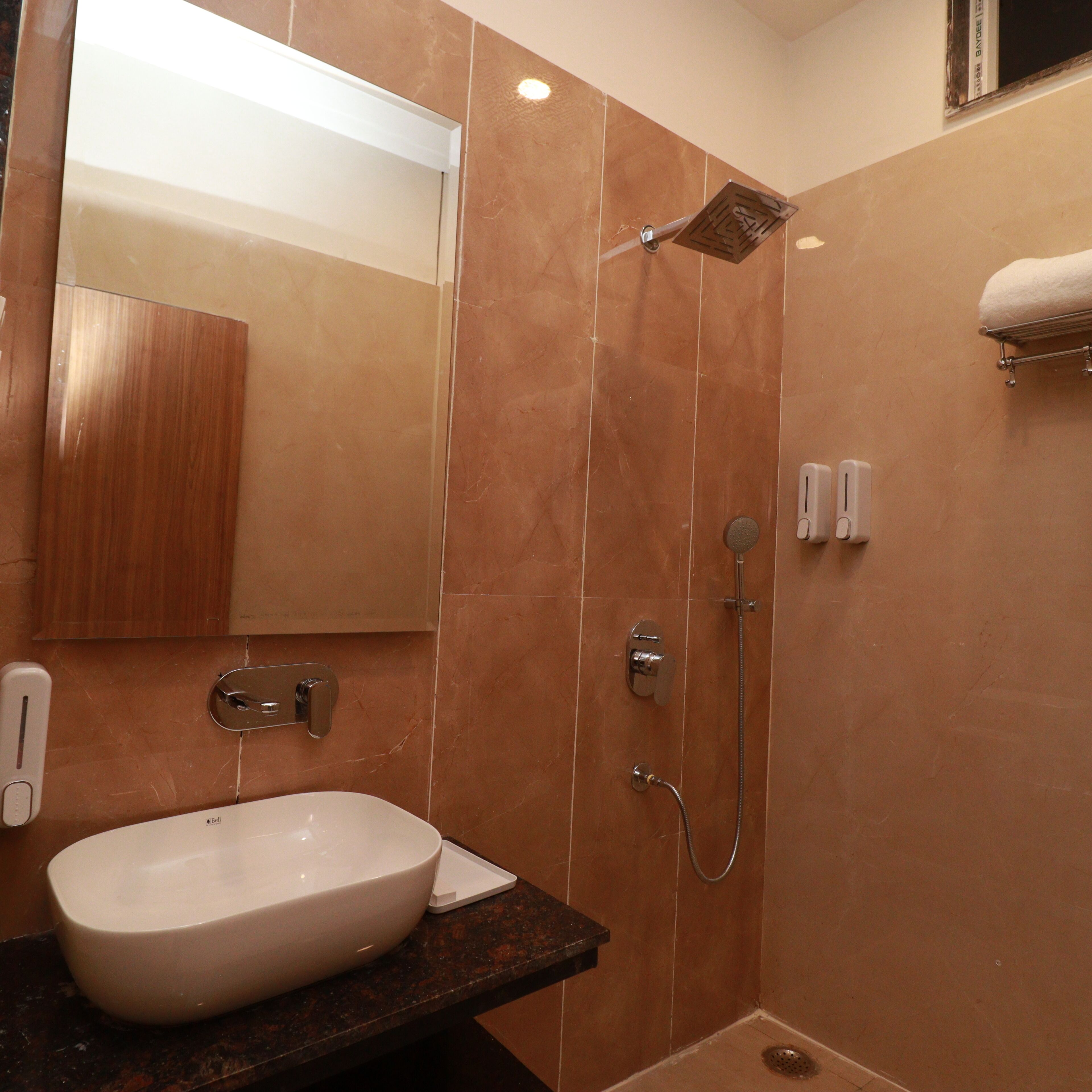 A bathroom with a large mirror, a sink, a shower, and a towel rack.