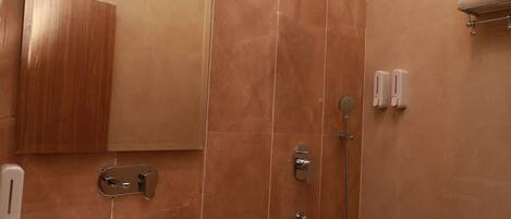A bathroom with a large mirror, a sink, a shower, and a towel rack.