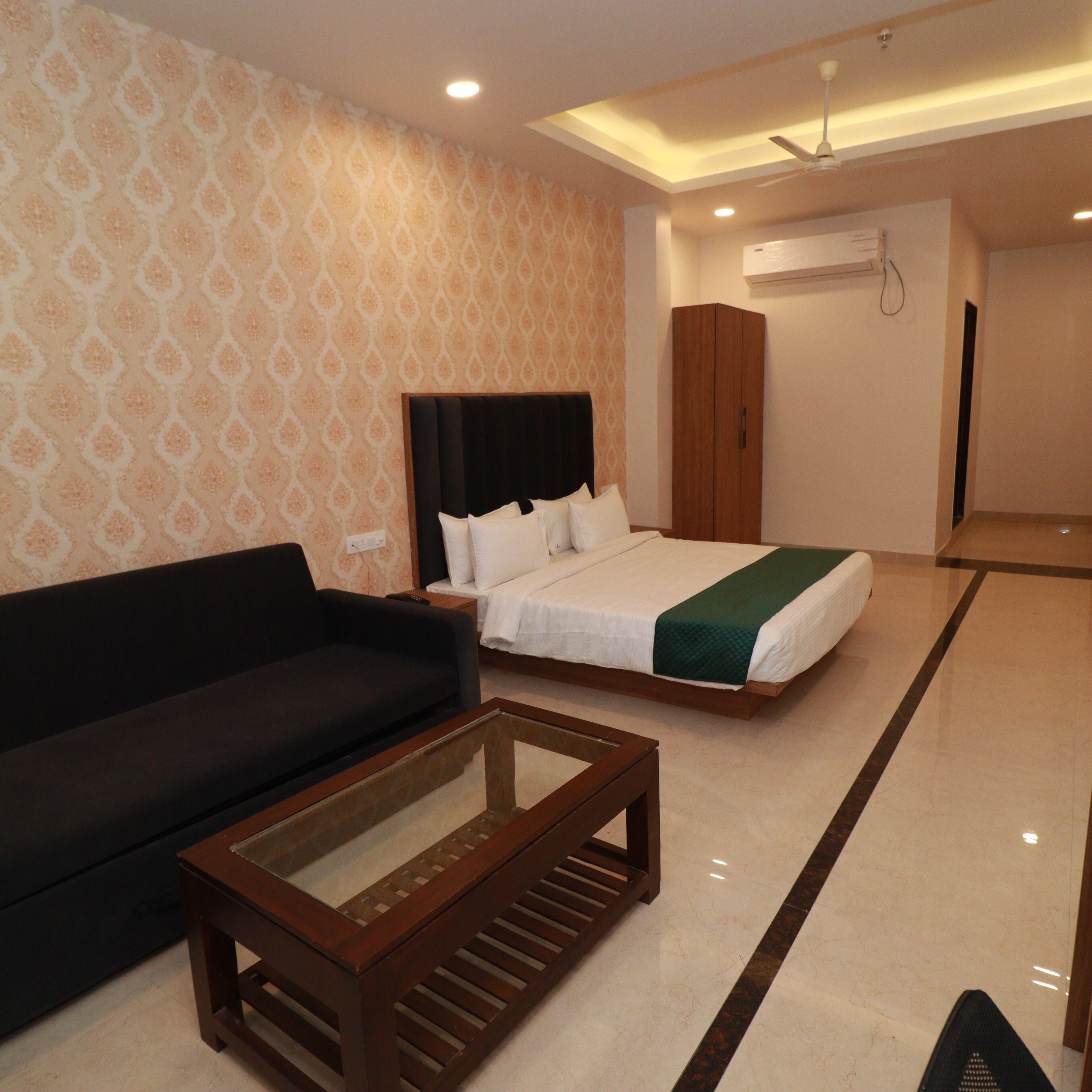 A hotel room with a bed, a sofa, a coffee table, and a wardrobe.