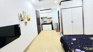 A hotel room with a bed, a TV, a kitchenette, and a wardrobe. - Ruby Relax Home (Hanoi)