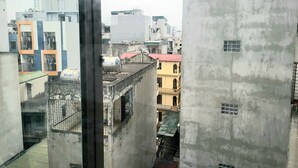 A view of a cityscape with various buildings, including a yellow building with a balcony and a white building with a red roof. - Ruby Relax Home (Hanoi)