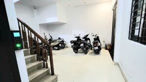 A clean, well-lit indoor space with a staircase leading to a lower level. Several motorcycles are parked in the area. - Ruby Relax Home (Hanoi)