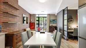 Een moderne keuken met een bakstenen muur, een eettafel met stoelen en een koelkast.