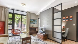 Een moderne woonkamer met een bank, een salontafel, een televisie, een boekenkast en een eethoek met een tafel en stoelen.