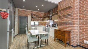 Een moderne keuken met een bakstenen muur, roestvrijstalen apparatuur en een eethoek met een tafel en stoelen.