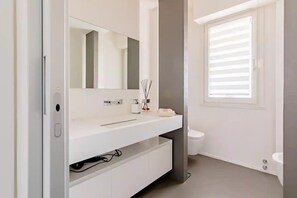 Ein modernes Badezimmer mit einem weißen Waschtisch, einem großen Spiegel und einer Toilette.