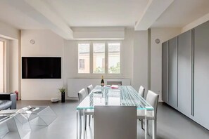 Ein modernes Wohnzimmer mit einem Glastisch, weißen Wänden und einem großen Fenster.