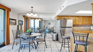 Una cocina moderna con una isla central, electrodomésticos de acero inoxidable y un comedor con una mesa redonda y sillas.