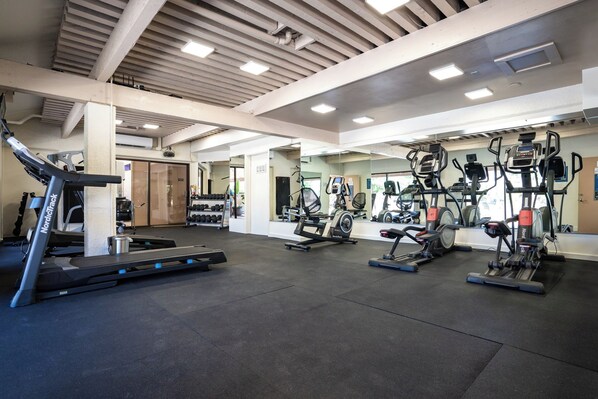 A gym with treadmills, elliptical machines, and free weights.