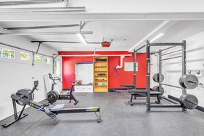 A gym with exercise equipment, a red wall, and a door leading to another room.