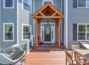 A house with a covered porch, a front door, and a grill.