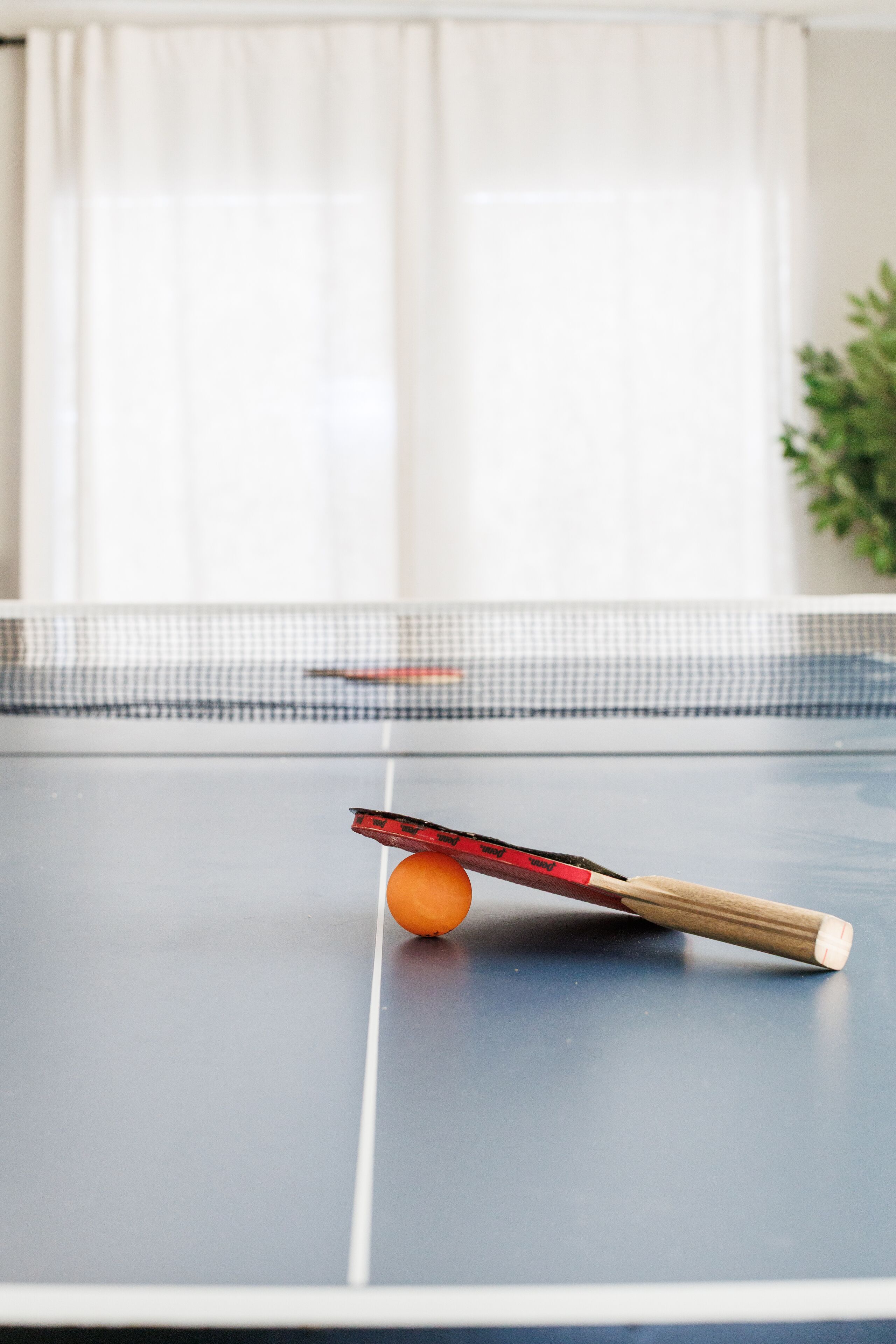 Une table de ping-pong avec une balle et une raquette au premier plan.
