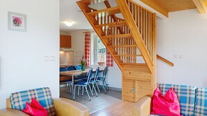 A modern interior with a wooden staircase, a dining area with blue chairs, and a sofa with plaid cushions. - Holiday Hill 56 by Interhome (Cerny Dul/Cista)