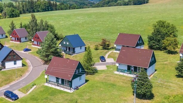 A rural area with several houses, each with a distinct architectural style, surrounded by green fields and trees. - Holiday Hill 56 by Interhome (Cerny Dul/Cista)