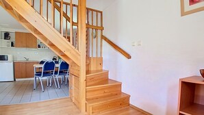 A wooden staircase leading to a kitchen area with a dining table and chairs. - Holiday Hill 56 by Interhome (Cerny Dul/Cista)