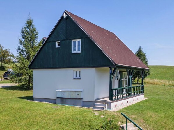 Situated in a serene grassy field, this charming building offers a cozy porch with a bench.