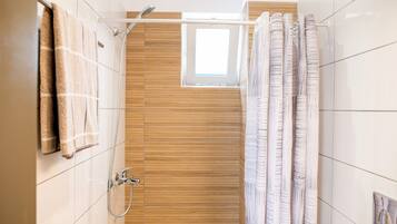 A modern bathroom with a shower, wooden paneling, and a window.