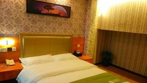 A hotel room with a large bed, a nightstand with a phone, and a painting on the wall.