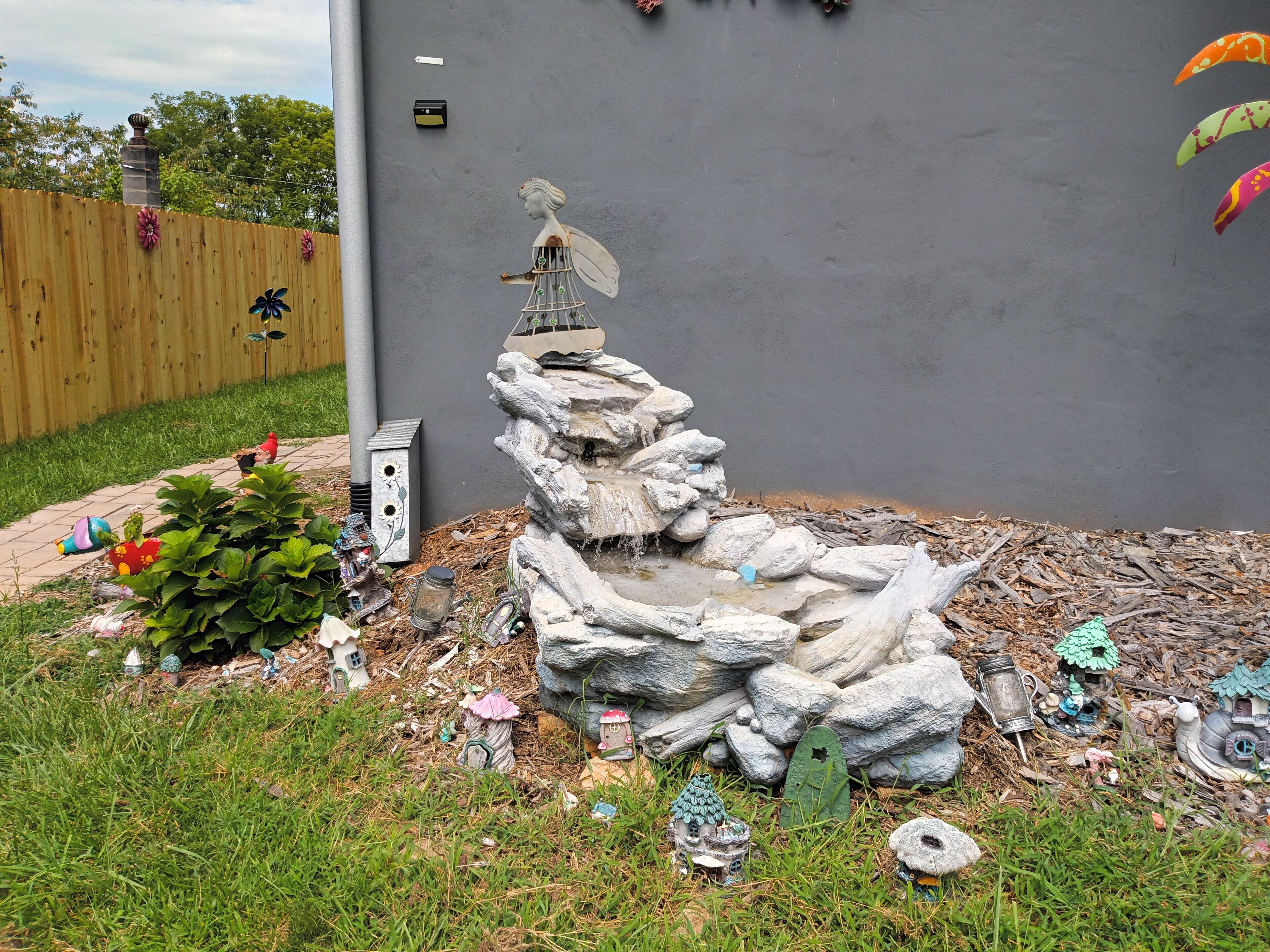 A garden with a rock formation, birdhouses, and a statue.