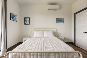 Une chambre bien rangée, avec un lit, des tables de chevet et des tableaux encadrés accrochés aux murs.