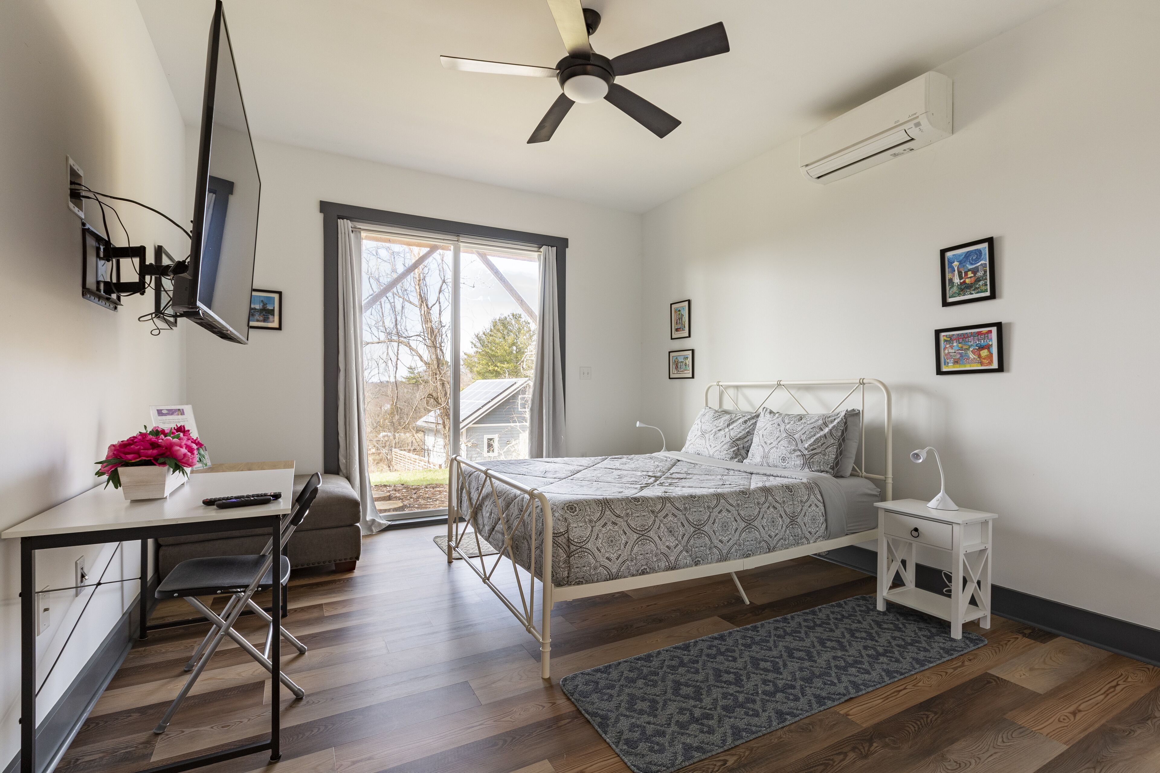 Un dormitorio con cama, escritorio, silla y ventilador de techo.
