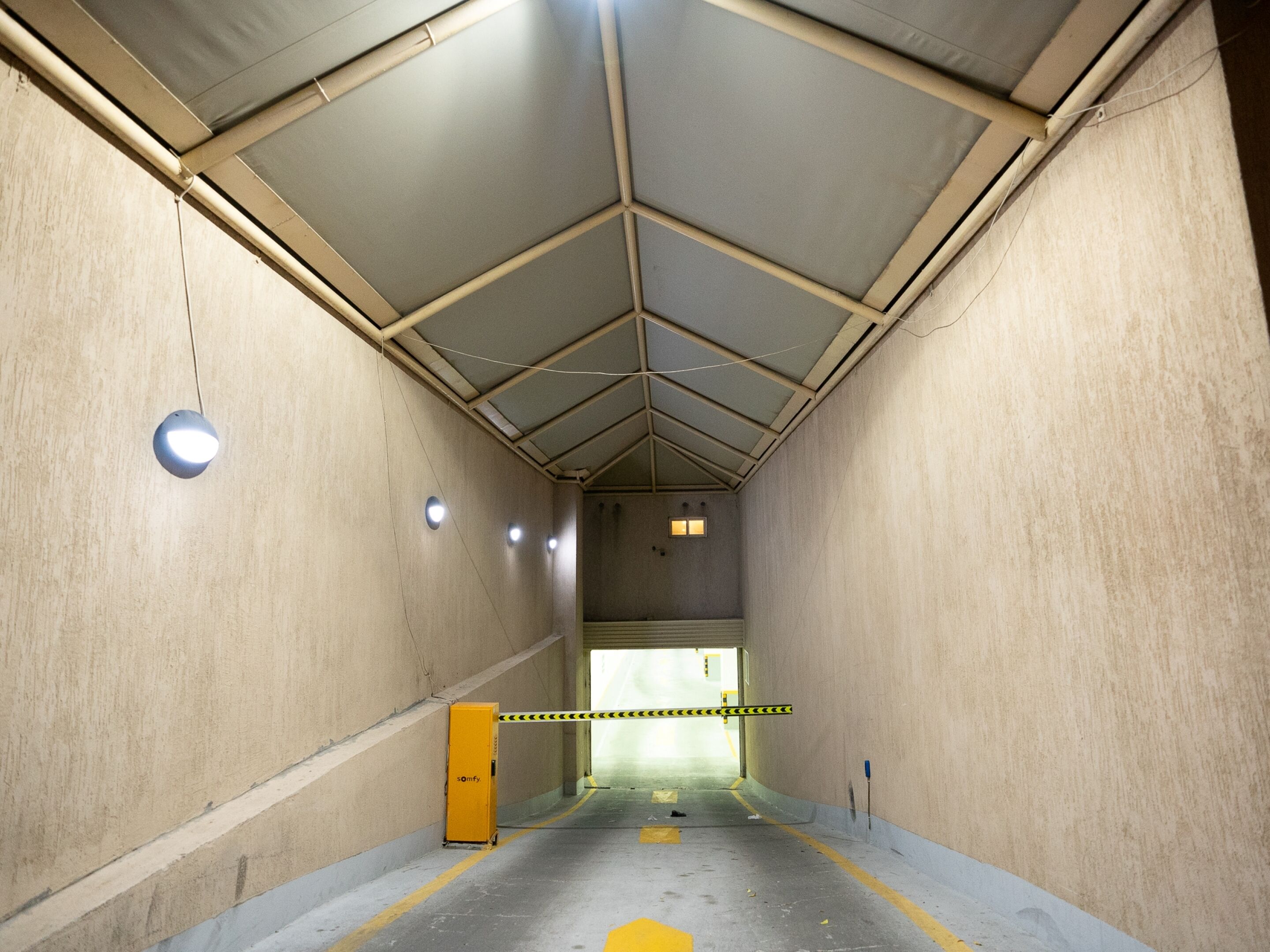 A tunnel-like interior with concrete walls, a metal ceiling, and a yellow safety barrier.