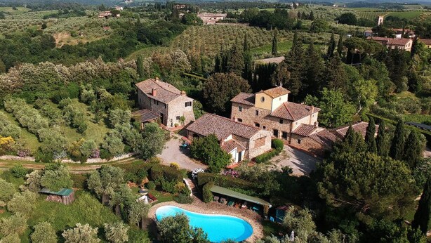 Une villa avec piscine, entourée d’une végétation luxuriante et avec des collines en arrière-plan.