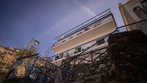 Un edificio de varios pisos con balcones, una escalera de piedra y cielo despejado.