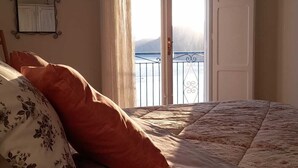 Un dormitorio con cama, espejo y balcón con vistas.