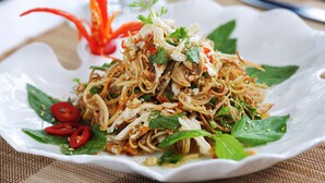 A plate of noodles garnished with herbs and chili slices. - Bigfun Cruises (Tuan Chau)